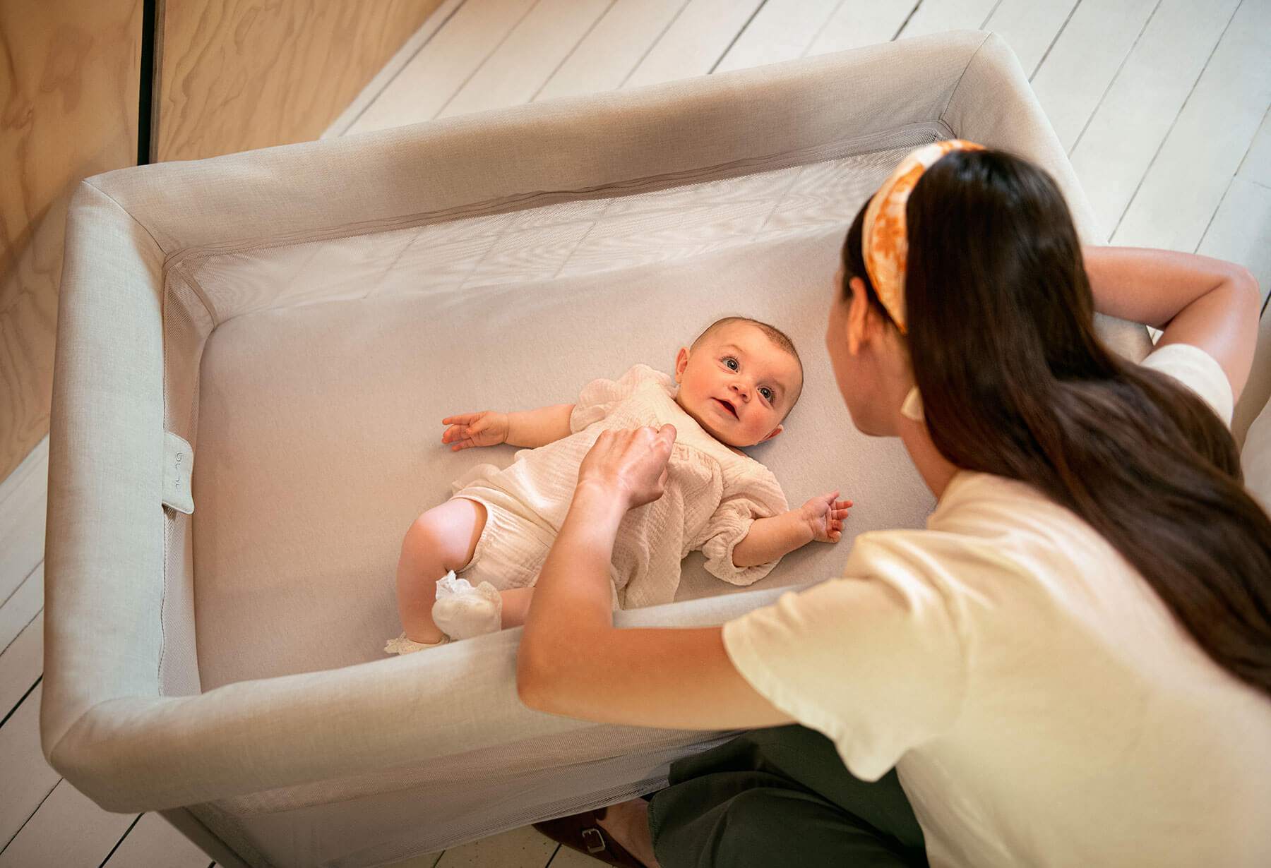 Woman looks at baby resting in the PAAL basinet